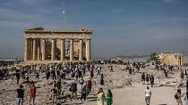 Tourists visit the Acropolis hill with the 2,500-year-old Parthenon temple on the left, and the ancient Erechtheion temple on the right, in Athens, Greece, on Oct. 11, 2022.