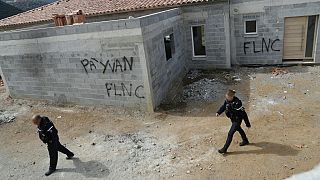 French gendarmes inspect a damaged private property in Corcisa defaced with graffiti reading "For Yvan - FLNC".