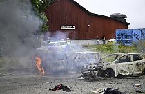 Police stand near the gutted remains of cars, at the Eritrean cultural festival "Eritrea Scandinavia" in Stockholm Thursday, Aug. 3, 2023.