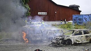 Police stand near the gutted remains of cars, at the Eritrean cultural festival "Eritrea Scandinavia" in Stockholm Thursday, Aug. 3, 2023.