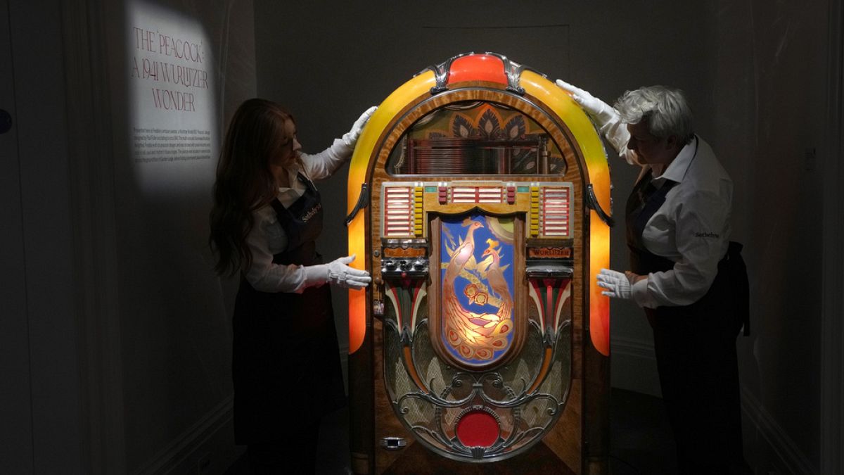 Sotheby's handlers stand with a A Wurlitzer Model 850 'Peacock' design jukebox by Paul Fuller, American, circa 1941, at Sotheby's auction rooms in London, Thursday, Aug. 3.