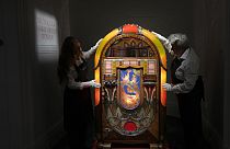 Sotheby's handlers stand with a A Wurlitzer Model 850 'Peacock' design jukebox by Paul Fuller, American, circa 1941, at Sotheby's auction rooms in London, Thursday, Aug. 3.