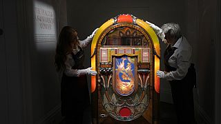 Sotheby's handlers stand with a A Wurlitzer Model 850 'Peacock' design jukebox by Paul Fuller, American, circa 1941, at Sotheby's auction rooms in London, Thursday, Aug. 3.