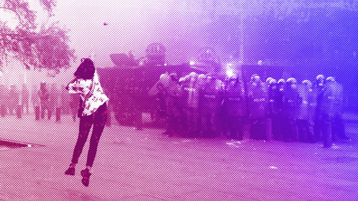 An anti-government protester woman throws a stone towards riot police during a protest near Parliament Square, in Beirut, September 2020