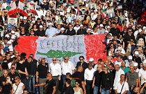 متظاهرون يرفعون الأعلام واللافتات التي تصور ضحايا تفجير ميناء بيروت عام 2020 خلال مسيرة بالقرب من ميناء العاصمة اللبنانية في 4 أغسطس 2023