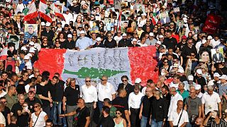 متظاهرون يرفعون الأعلام واللافتات التي تصور ضحايا تفجير ميناء بيروت عام 2020 خلال مسيرة بالقرب من ميناء العاصمة اللبنانية في 4 أغسطس 2023