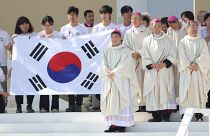 Peregrinos e bispos posam para fotografia, segurando bandeira sul-coreana, país que vai receber as próximas JMJ, durante missa de encerramento da JMJ, Lisboa, 6 de agosto 2023