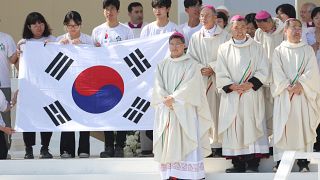 Peregrinos e bispos posam para fotografia, segurando bandeira sul-coreana, país que vai receber as próximas JMJ, durante missa de encerramento da JMJ, Lisboa, 6 de agosto 2023