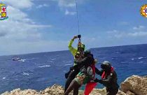 A migrant stranded on a rocky reef on the tiny Italian southern island of Lampedusa, Sicily is plucked to safety by helicopter.