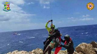 A migrant stranded on a rocky reef on the tiny Italian southern island of Lampedusa, Sicily is plucked to safety by helicopter.