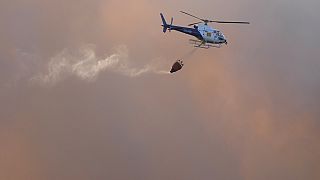 Ein Löschhubschrauber fliegt inmitten der Rauchwolken eines Waldbrandes in Alcabideche -  Archiv