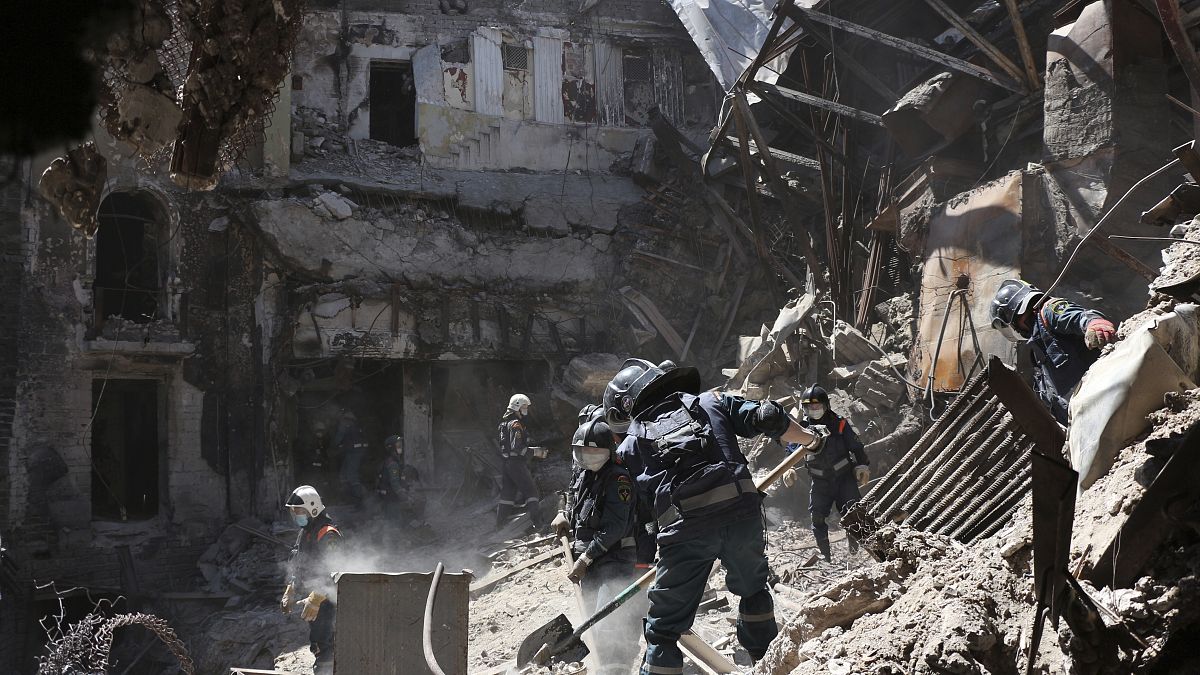 Empleados del Ministerio de Situaciones de Emergencia de la República Popular de Donetsk retiran escombros junto al teatro de Mariupol dañado en Mariupol.