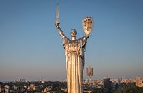 Trabalhadores instalam o brasão de armas ucraniano no escudo na mão da estatura mais alta do país, o Monumento à Pátria, 6 de agosto de 2023.