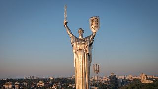 Trabalhadores instalam o brasão de armas ucraniano no escudo na mão da estatura mais alta do país, o Monumento à Pátria, 6 de agosto de 2023.