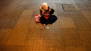 Женщина держит своего ребенка, чтобы попросить денег, недалеко от площади Таксим в Стамбуле, Турция, вторник, 18 июня 2013 г. 