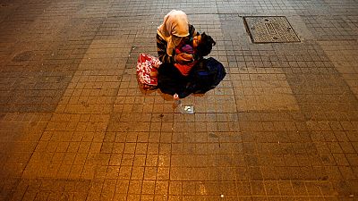 A woman holds her child to beg for money near Taksim Square in, Istanbul, Turkey, Tuesday, June 18, 2013. 