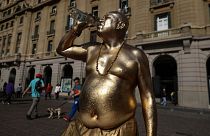 Живая статуя человека пьет из бутылки, отдыхая во время необычной для зимнего периода жары в Сантьяго, Чили, 4 августа 2023 г.