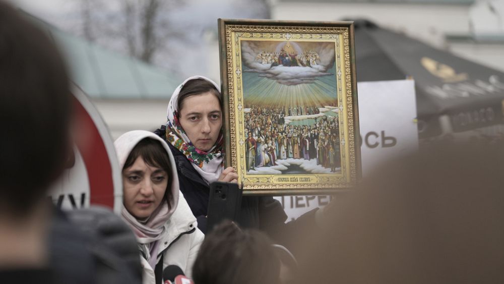 Поддръжник на Украинската православна църква държи икона пред манастирския комплекс