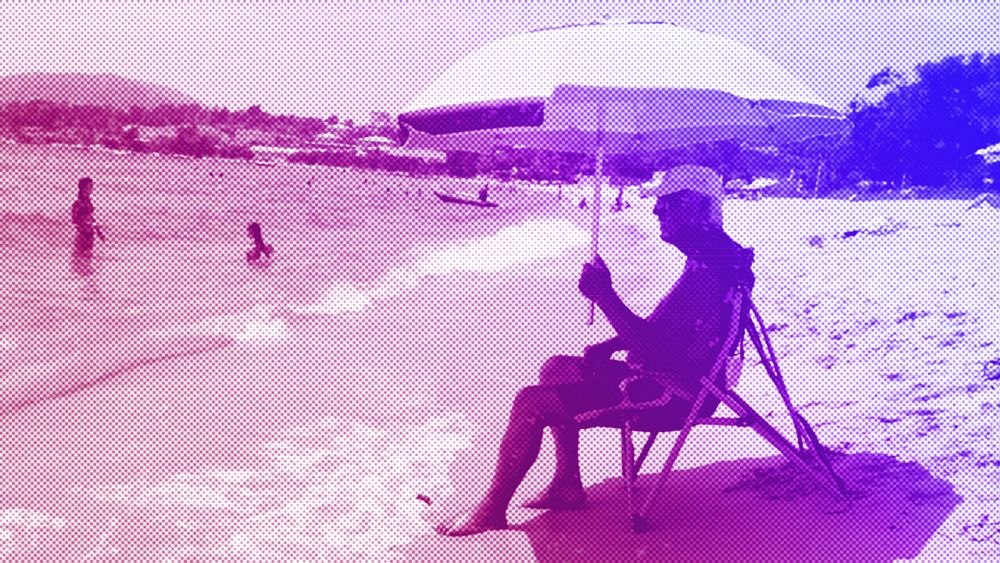 Мъж седи под сянката на чадър на плажа Риканто в
