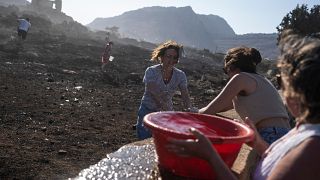 Turistas alemanes junto con residentes intentan extinguir un incendio, cerca de la localidad de Lindos, en la isla de Rodas, al sureste de Grecia, el 24 de julio de 2023.
