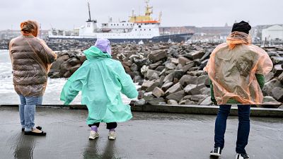Menschen stehen bei windigem Wetter auf der Außenmole des Hafens von Hirtshals in Dänemark