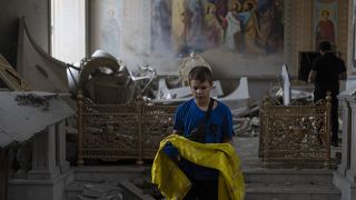Un garçon aide à récupérer des objets dans la cathédrale de la Transfiguration d'Odessa après qu'elle ait été lourdement endommagée par des attaques de missiles russes, 23 jui