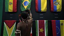 An indigenous man passes in a flag pavilion of the States parties to the Amazon Cooperation Treaty, during the Amazon Dialogue meetings in Belem, Brazil, Sunday, Aug. 6, 2023.