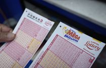 Lottery player Mariano Velasquez holds forms to pick numbers for the Powerball and Mega Millions lotteries as he buys tickets, Monday, Aug. 7, 2023