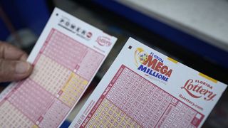 Lottery player Mariano Velasquez holds forms to pick numbers for the Powerball and Mega Millions lotteries as he buys tickets, Monday, Aug. 7, 2023