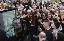 El coche con el féretro de Sinéad O'Connor, rodeado por su admiradores