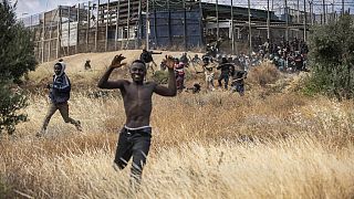 Migrantes corren en suelo español tras cruzar las vallas que separan el enclave español de Melilla de Marruecos en Melilla.