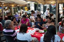 I turisti mangiano in una delle famose terrazze all'aperto di Barcellona.
