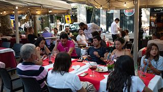 Des touristes mangent à l'une des terrasses en plein air les plus populaires de Barcelone.
