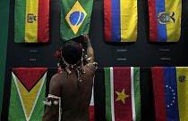 An indigenous man passes his hand over the Brazilian flag in a flag pavilion of the States parties to the Amazon Cooperation Treaty, during the Amazon Dialogue meetings.
