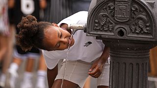 A girl drinks water from a public fountain tap in Madrid, Spain