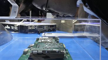 A visitor examines a computer chipset at the booth for Chinese semiconductor and chip developer Kunlunxin during the World AI Conference in Shanghai, Wednesday, July 5, 2023.