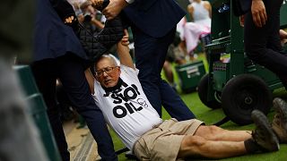 Un manifestante di Just Stop Oil viene trattenuto dal personale di sicurezza sul campo 18 durante Wimbledon a Londra. 