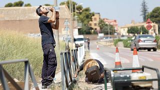 Pedro, 48, and Juan, 45, metal workers, repair a guardrail on the Burjassot road during a heat wave near Valencia, Spain July 18, 2023.