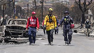 Members of a search-and-rescue team walk along a street, Saturday, Aug. 12, 2023, in Lahaina, Hawaii, following heavy damage caused by wildfire.