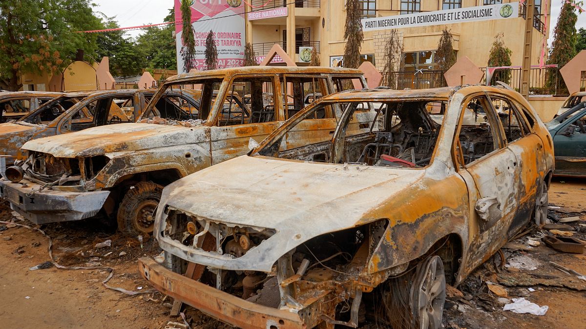 Kiégett autóroncsok a hatalmától megfosztott elnök pártjának niameyi székháza előtt 2023. augusztus 11-én