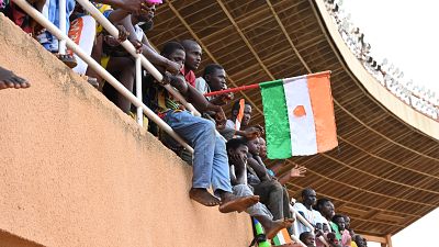 A man waves a Nigerien flag as supporters cheer from the stands while artists perform during a concert in support to Niger's National Council for the Safeguard of the Homeland