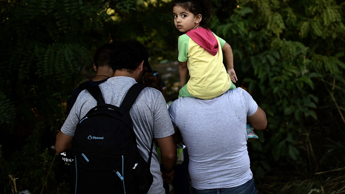 مهاجرون سوريون يسيرون على طول خط سكة حديد للعبور من صربيا إلى المجر. 