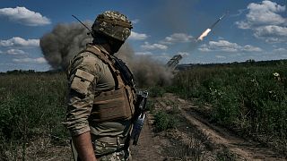 A Ukrainian soldier watches a Grad multiple launch rocket system firing shells with flyers near Bakhmut, Donetsk region, Ukraine, Sunday, Aug. 13, 2023