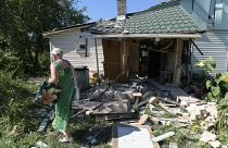 Мать осматривает разрушенный дом сына, погибшего при обстреле Донецка