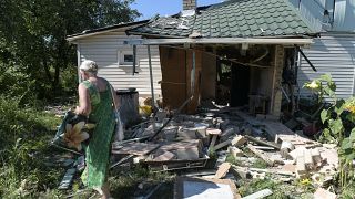 Мать осматривает разрушенный дом сына, погибшего при обстреле Донецка