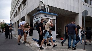 Fußballfans, die meisten von ihnen aus Kroatien, bedecken ihre Gesichter vor der Allgemeinen Polizeidirektion in Attika.