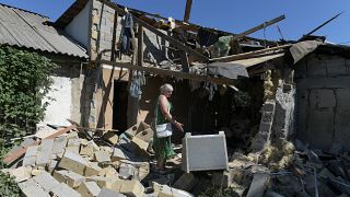 Lyubov Tolchina, 63, reacts as she stands amongst the rubble-strewn in the garden of her son's home, in the Russian-controlled Donetsk, in eastern Ukraine
