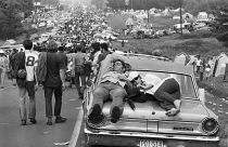 Woodstock attendees catch a nap on top of a car, 1969