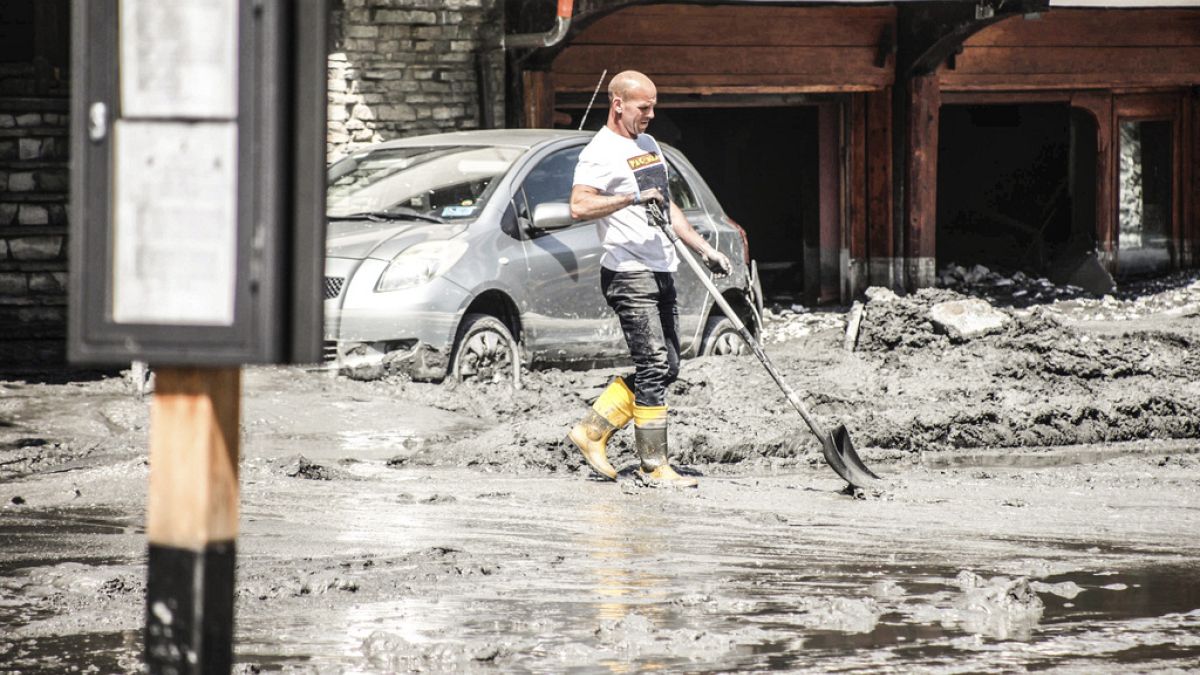 A resident clears mud and debris covering the streets, following a mountain mudslide, which caused the flooding of a stream in Bardonecchia.