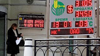 A woman leaves an exchange booth of a bank in Moscow, Tuesday, Jan. 20, 2009, with signs indicating the U.S. dollar and euro exchange rates.